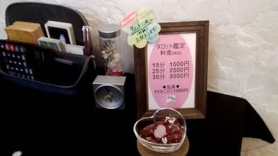 妃彩江先生が営む占い喫茶「安里彩」店内の占いテーブルと鑑定料のプレート